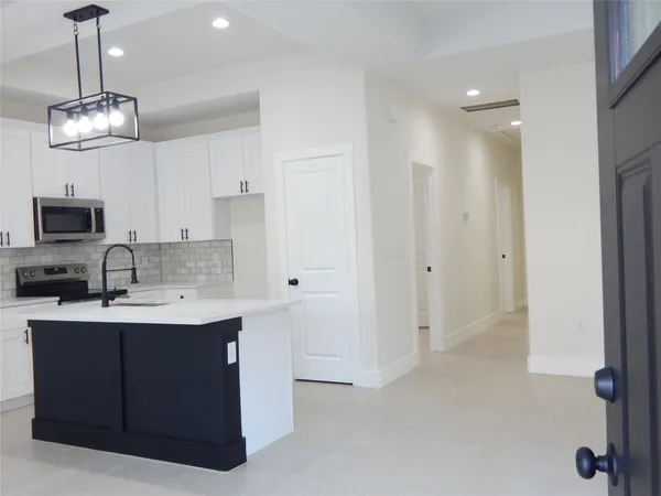 a kitchen with kitchen island stainless steel appliances a sink dishwasher a refrigerator and a stove with wooden floor