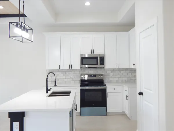 a kitchen with stainless steel appliances a stove a sink and white cabinets