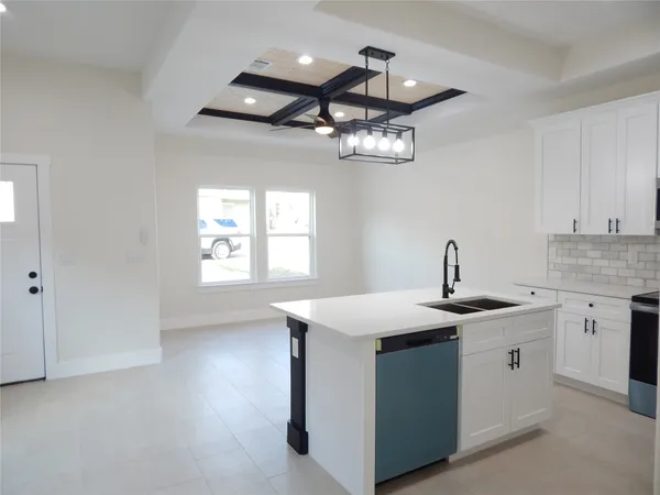a kitchen with stainless steel appliances granite countertop a sink dishwasher a stove and a dining table with wooden floor