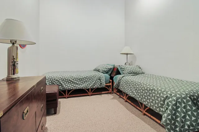 a bedroom with two beds and a lamp on the dresser