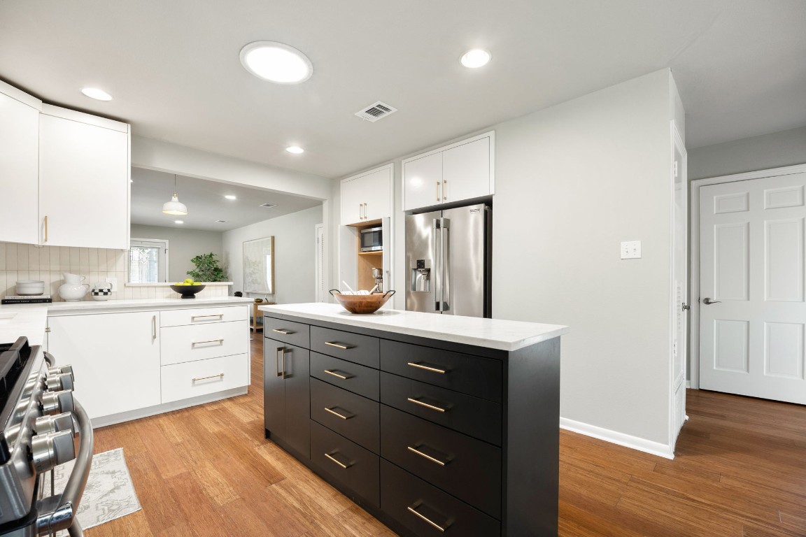 1601 Northridge Drive Austin, TX 78723 - Photo 11 of 40 a large white kitchen with a stove a sink dishwasher and a refrigerator with wooden floor
