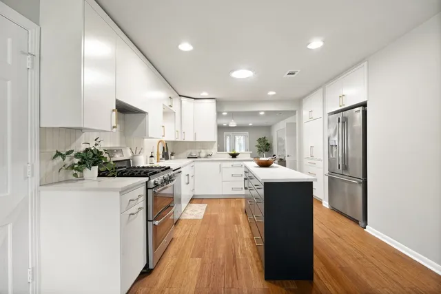 a kitchen with kitchen island a counter top space a sink cabinets and stainless steel appliances