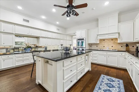 a kitchen with stainless steel appliances a dining table chairs sink and cabinets
