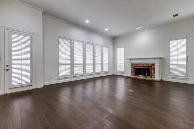an empty room with wooden floor fireplace and windows