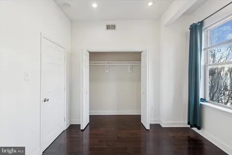 an empty room with wooden floor cabinet and windows