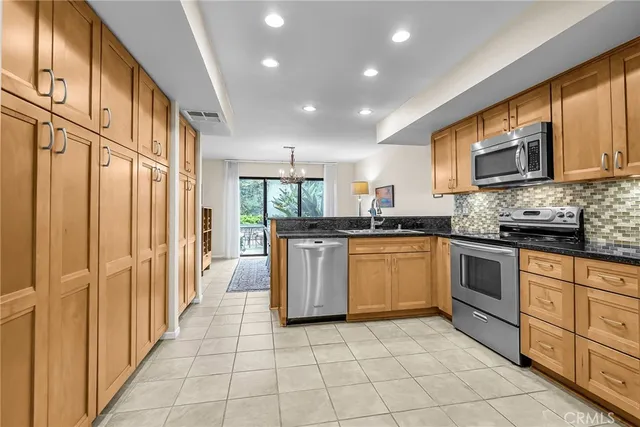 a kitchen with stainless steel appliances granite countertop a stove a sink and a microwave