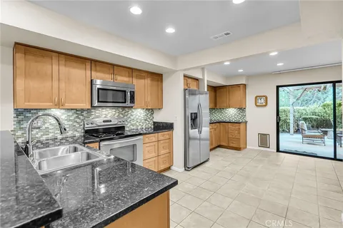 a kitchen with stainless steel appliances granite countertop a sink dishwasher stove and refrigerator