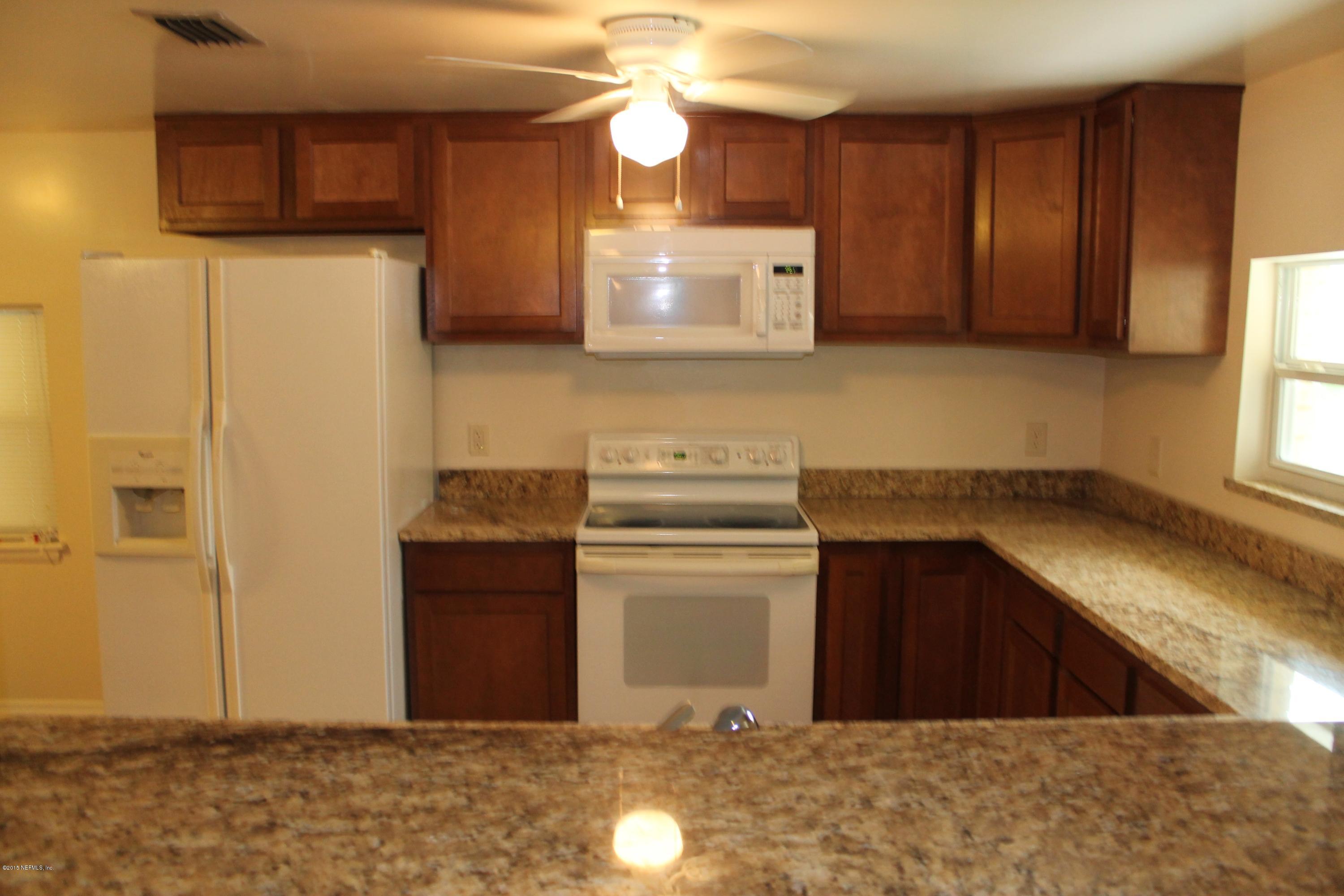 6207 Lone Star Road Jacksonville, FL 32211 - Photo 18 of 35 a kitchen with stainless steel appliances granite countertop a refrigerator a stove and a sink with wooden cabinets