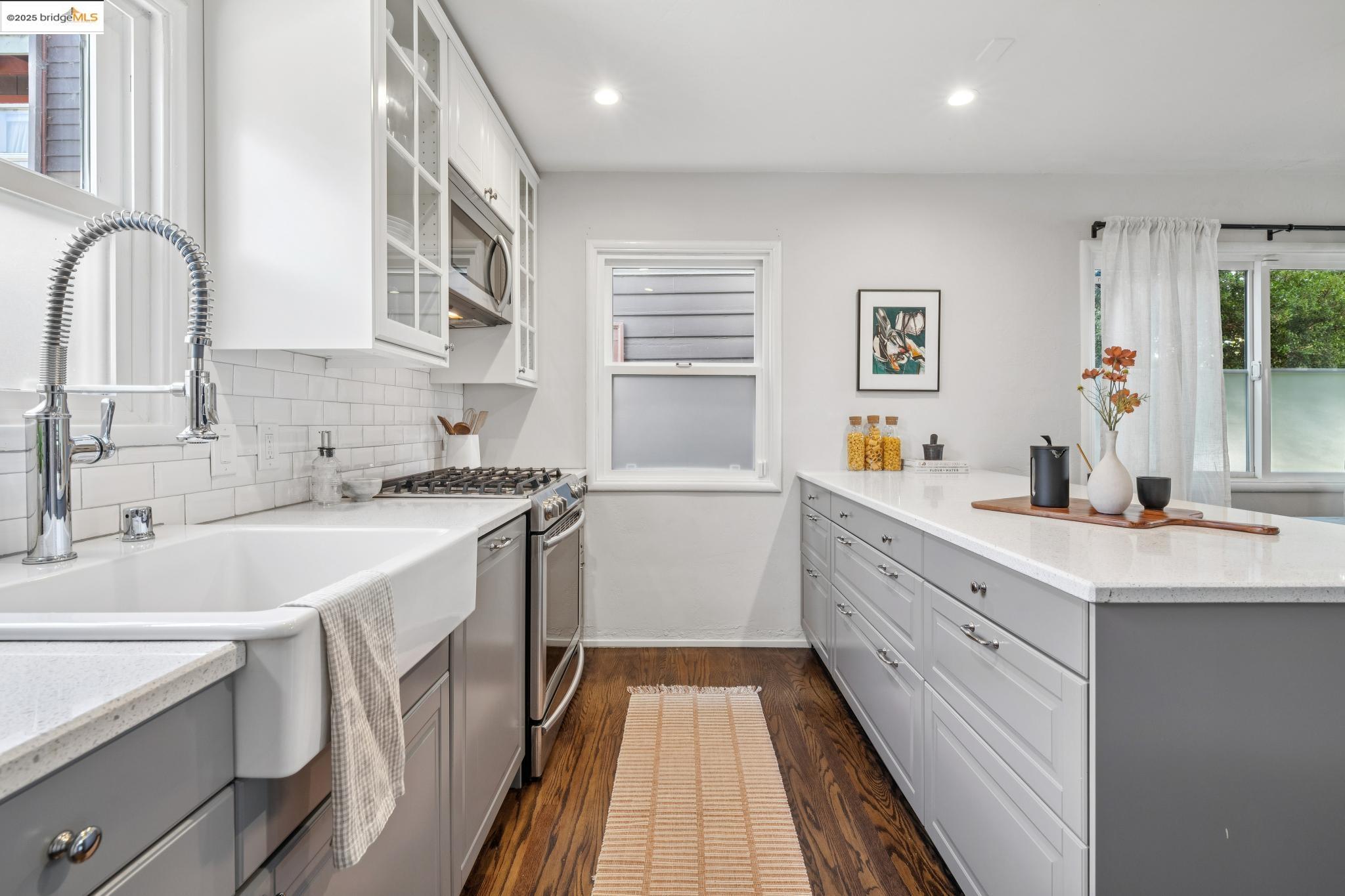 4170 Emerald Street, Unit 4 Oakland, CA 94609 - Photo 27 of 37 Kitchen featuring glass insert cabinets, gray cabinetry, dark wood-style floors, appliances with stainless steel finishes, and recessed lighting