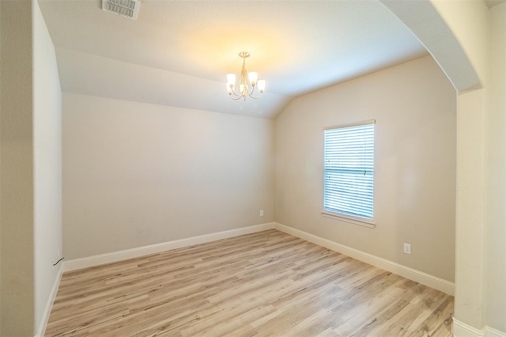 Vaulted ceiling, wood-finish flooring, arched entryway, window with blinds, and a decorative chandelier