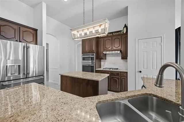 a kitchen with stainless steel appliances granite countertop a sink stove and refrigerator