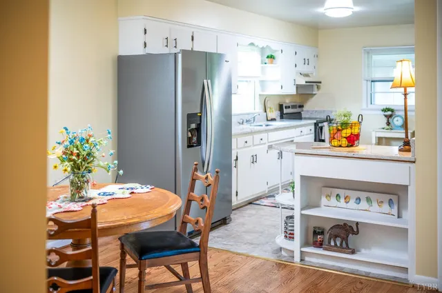 a kitchen with stainless steel appliances a dining table chairs refrigerator and sink