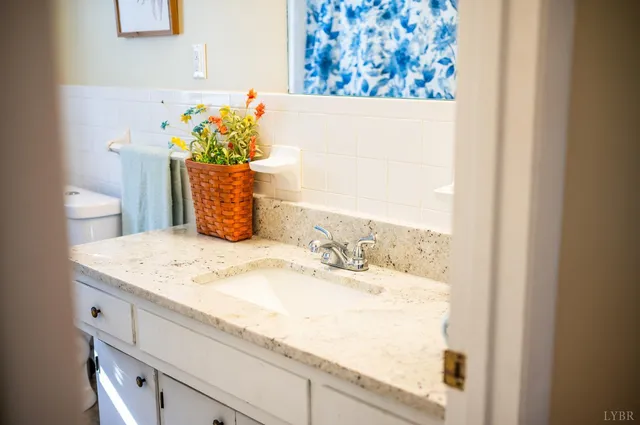 a bathroom with a granite countertop sink a toilet and a mirror
