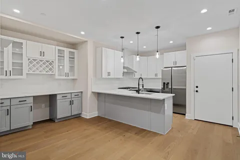a kitchen with stainless steel appliances granite countertop a sink a stove a refrigerator and white cabinets