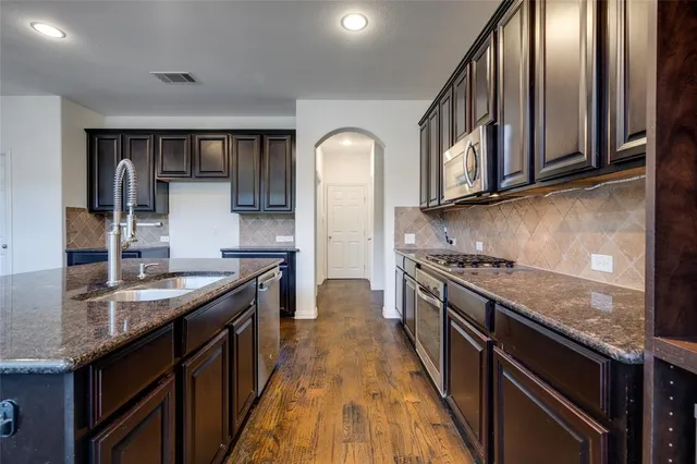 a kitchen with granite countertop white cabinets and black appliances