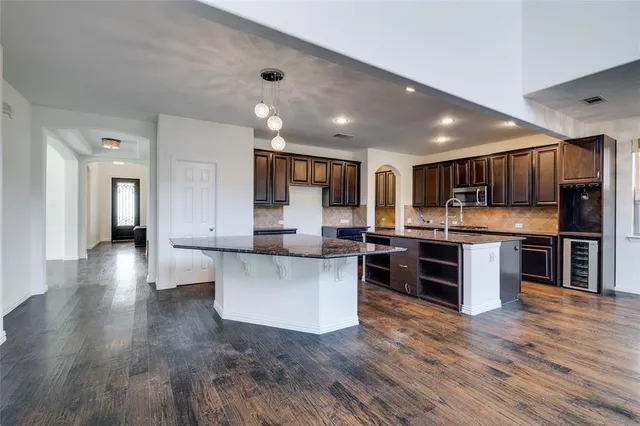 a kitchen with stainless steel appliances granite countertop wooden cabinets a refrigerator and a sink