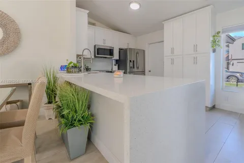 a kitchen with stainless steel appliances a sink a microwave a refrigerator and a counter top space