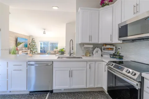 a kitchen with granite countertop a sink stainless steel appliances and cabinets