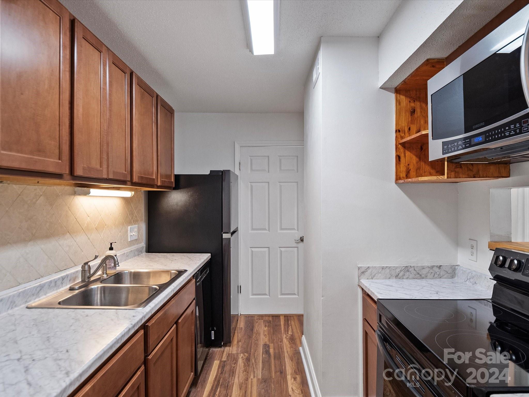 4906 Sardis Road, Unit F Charlotte, NC 28270 - Photo 14 of 30 a kitchen with stainless steel appliances granite countertop a sink stove and refrigerator