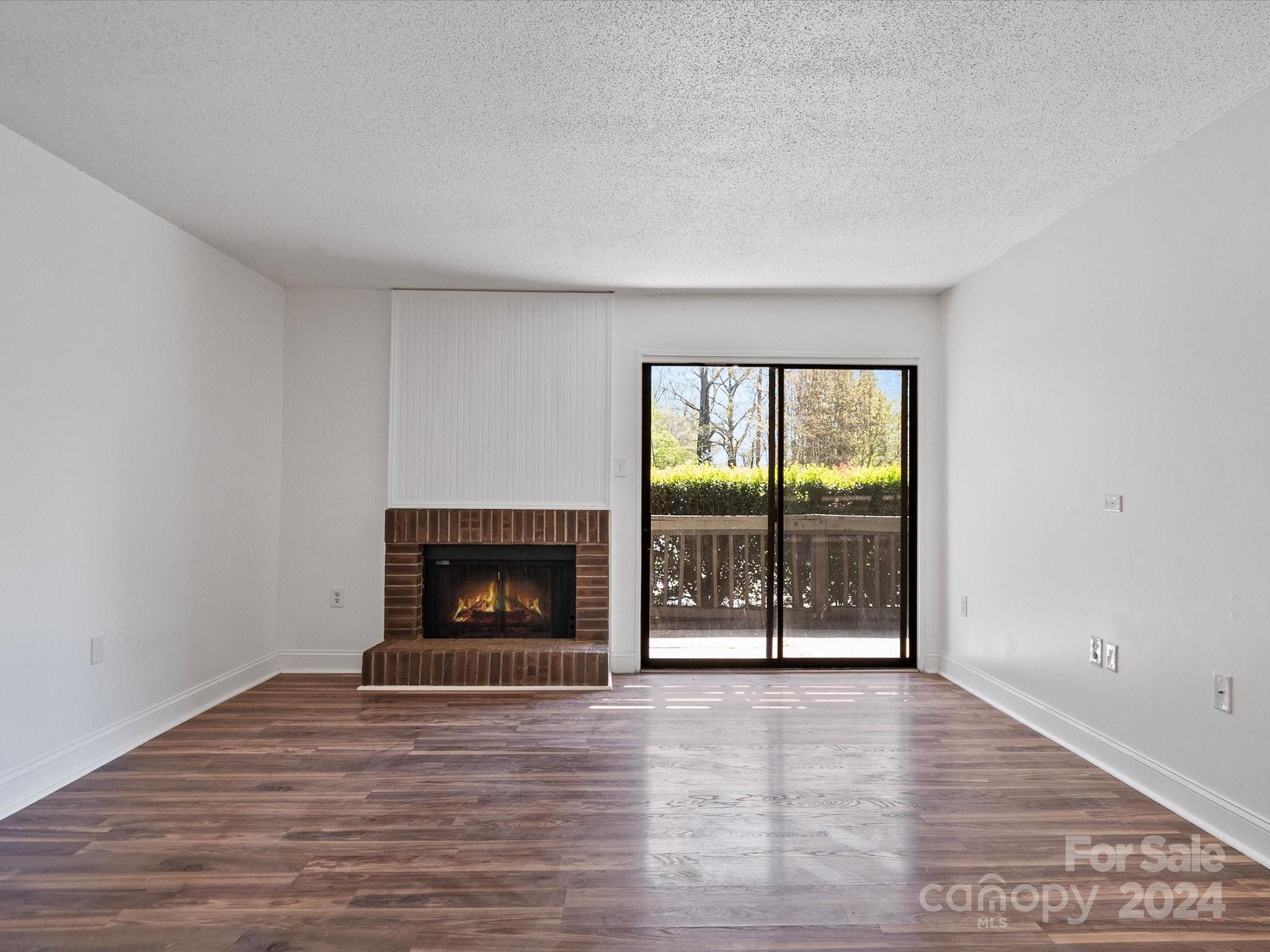 4906 Sardis Road, Unit F Charlotte, NC 28270 - Photo 2 of 30 an empty room with wooden floor fireplace and windows