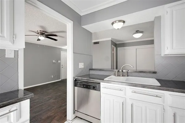 a kitchen with granite countertop a sink cabinets and stainless steel appliances
