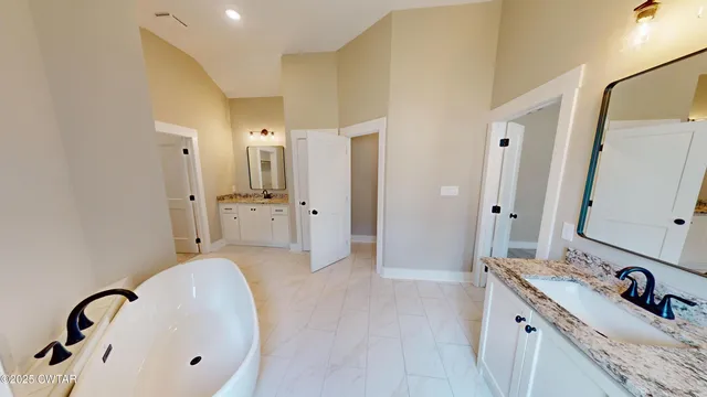 a view of a hallway with wooden floor and a bathroom