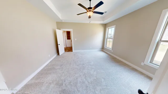 an empty room with windows and fan