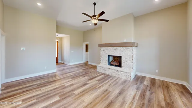 a view of an empty room with wooden floor and a fireplace