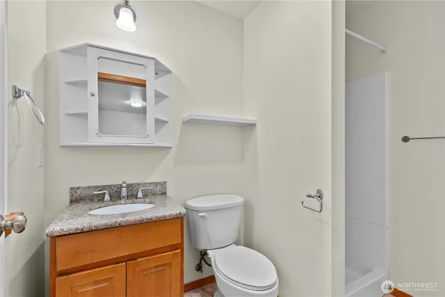 a bathroom with a granite countertop toilet sink and mirror