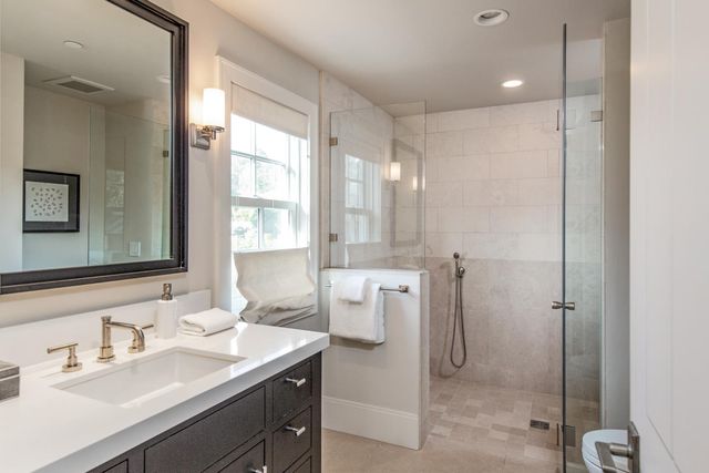 a bathroom with a shower sink vanity and mirror