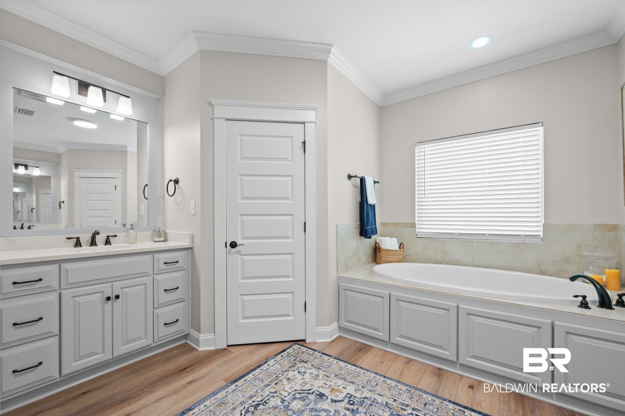 409 Fortune Drive Fairhope, AL 36532 - Photo 19 of 42 Bathroom featuring a built-in soaking tub with surrounding cabinetry, a single vanity with stone countertop, and wood-finish flooring