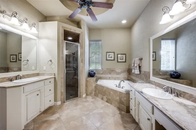 a large bathroom with a granite countertop double vanity sink a mirror and a bathtub