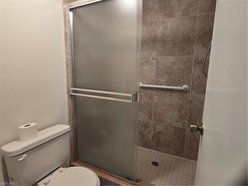 5737 Whitaker Road, Unit C104 Naples, FL 34112 - Photo 25 of 35 Shower enclosure featuring a frosted glass door, grab bar, and tiled surround