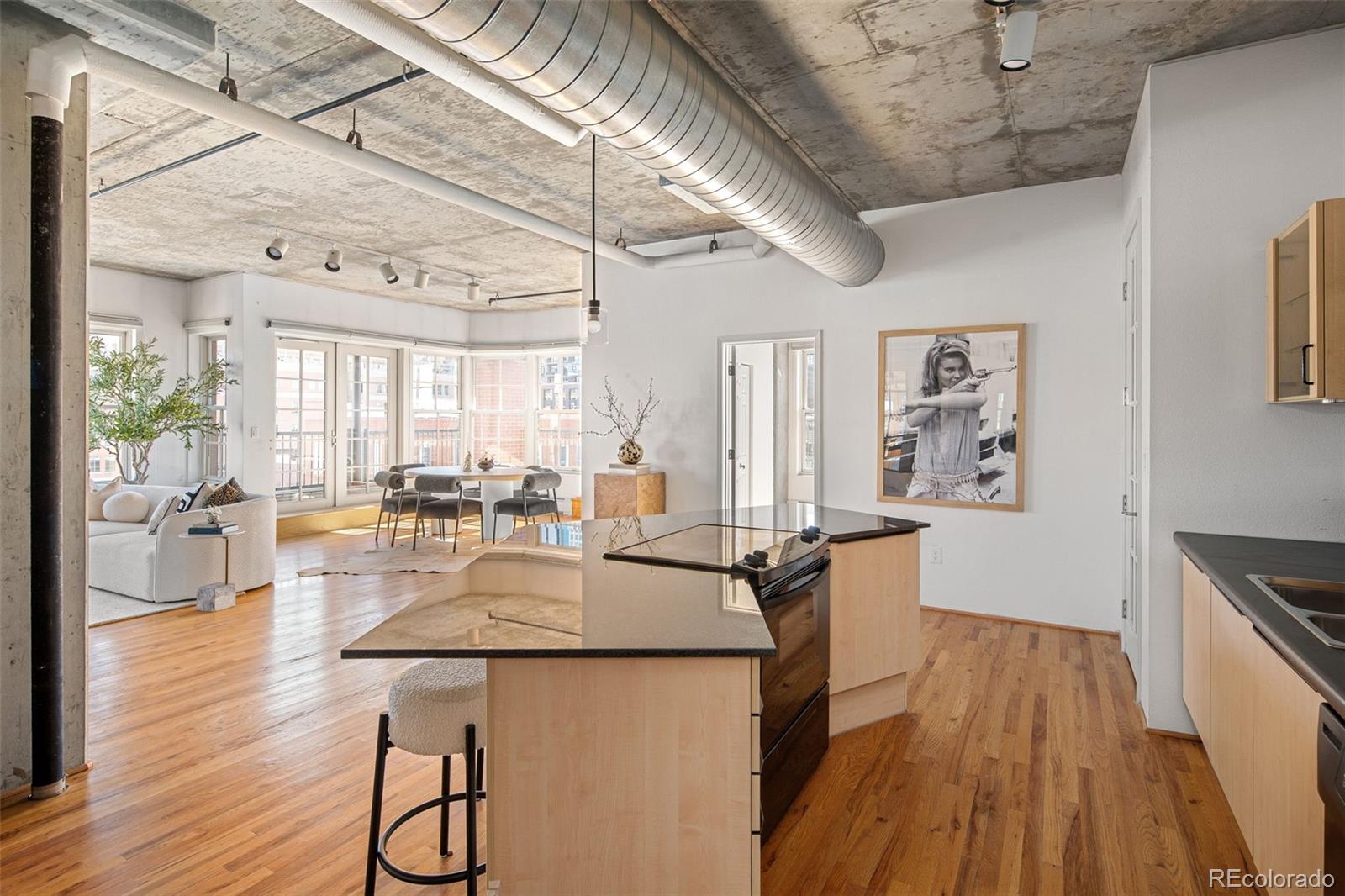 1499 Blake Street, Unit 6A Denver, CO 80202 - Photo 23 of 46 a dining hall with stainless steel appliances granite countertop a stove a refrigerator a dining table and chairs with wooden floor