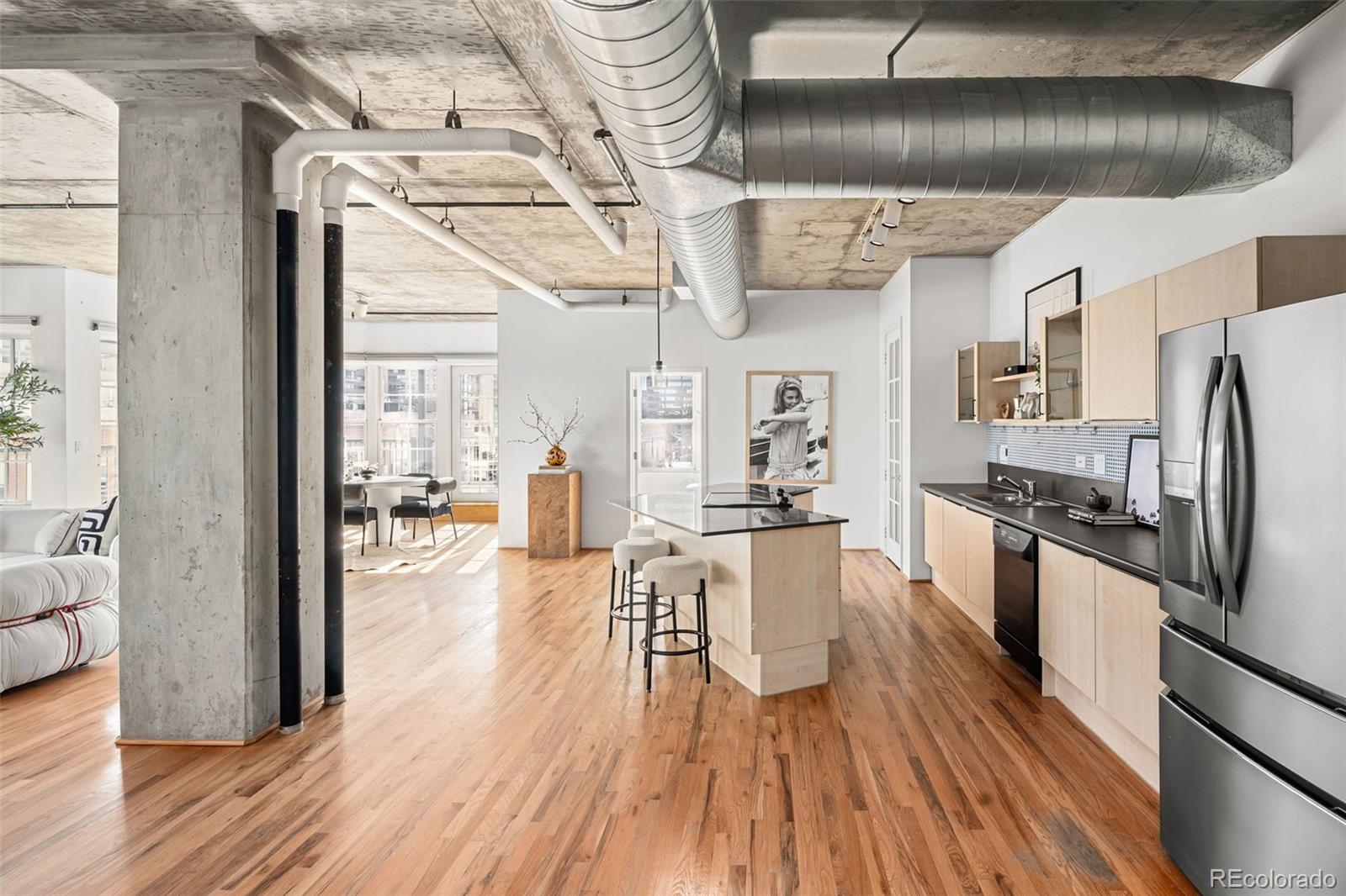 1499 Blake Street, Unit 6A Denver, CO 80202 - Photo 40 of 46 a kitchen with stainless steel appliances granite countertop a refrigerator a stove oven and white countertops with wooden floor