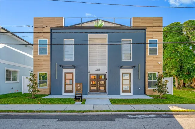 a view of a brick house with a yard large tree and plants