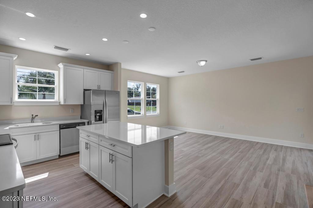3666 Eunice Road Jacksonville, FL 32250 - Photo 12 of 32 a large white kitchen with stainless steel appliances granite countertop a sink and a stove with wooden floors