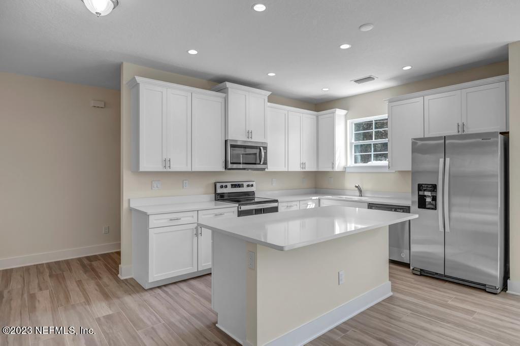 3666 Eunice Road Jacksonville, FL 32250 - Photo 10 of 32 a kitchen with stainless steel appliances granite countertop a refrigerator a sink dishwasher a s stove top oven a large island with white cabinets and wooden floor