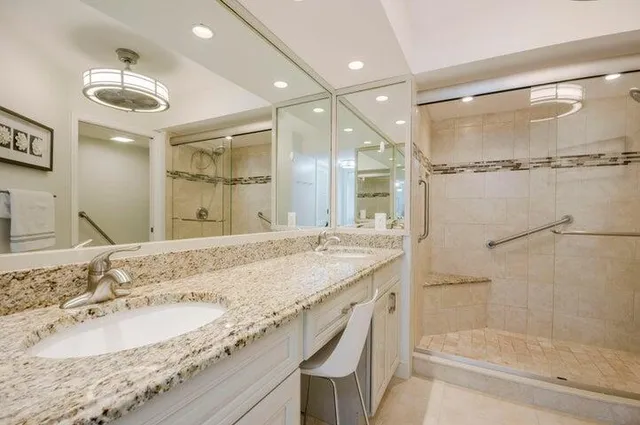 a bathroom with a granite countertop double vanity and a shower