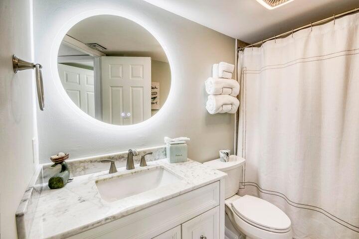 9600 South Ocean Drive, Unit 306 Jensen Beach, FL 34957 - Photo 27 of 36 a bathroom with a granite countertop sink mirror vanity and toilet