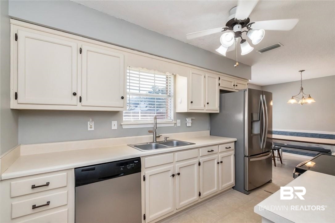 6601 Conde Court Mobile, AL 36695 - Photo 10 of 30 Kitchen with stainless steel appliances, hanging light fixtures, ceiling fan with notable chandelier, white cabinets, and sink