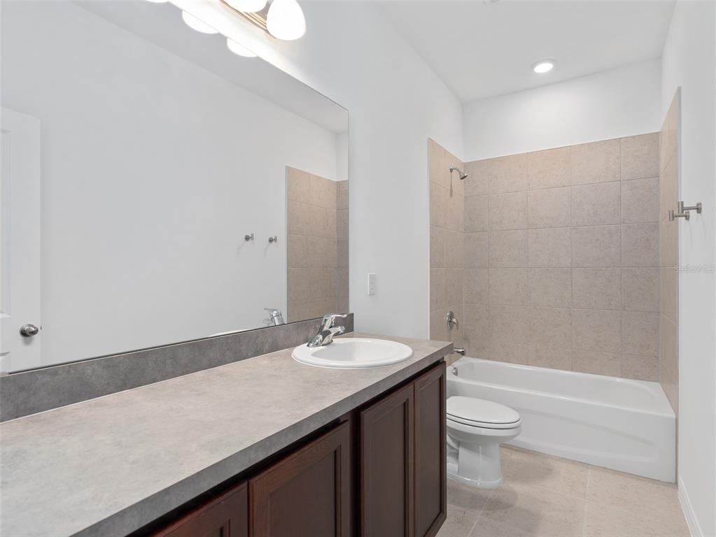 1122 Pearl Tree Road Deltona, FL 32725 - Photo 23 of 30 a bathroom with a granite countertop sink a toilet and shower