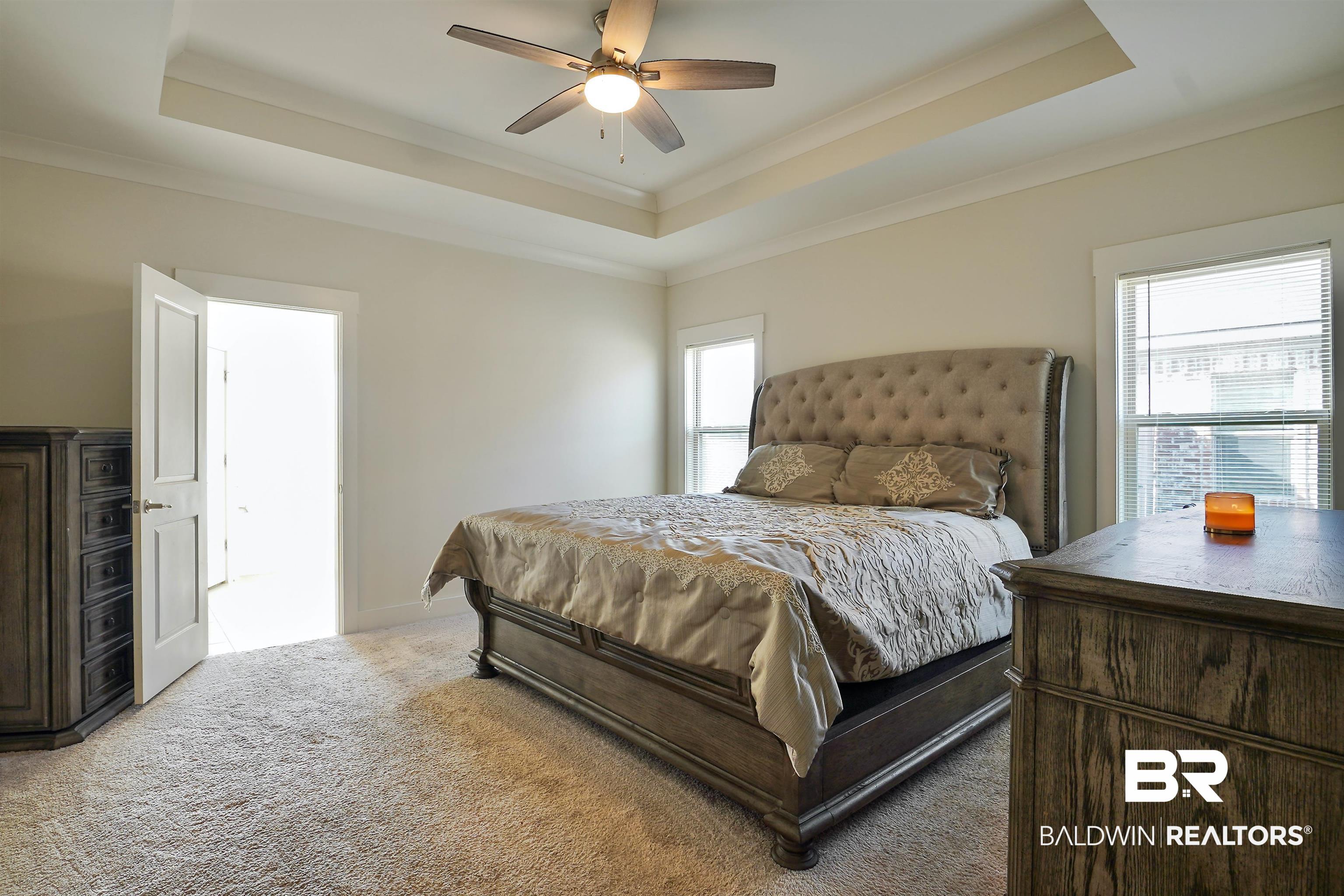 7090 Rocky Rd Loop Gulf Shores, AL 36542 - Photo 13 of 34 Bedroom featuring ceiling fan, a raised ceiling, light colored carpet, and ornamental molding
