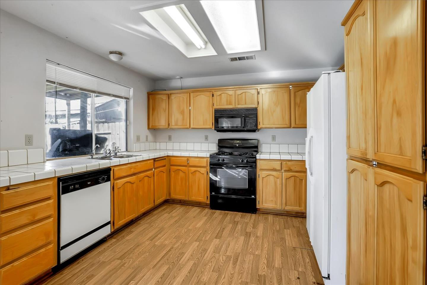 2113 Manhattan Way Modesto, CA 95358 - Photo 7 of 17 a kitchen with stainless steel appliances a sink cabinets and a wooden floor