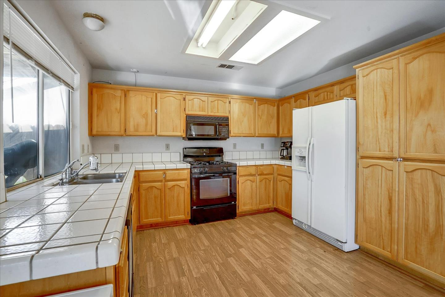 2113 Manhattan Way Modesto, CA 95358 - Photo 8 of 17 a kitchen with a refrigerator a stove top oven a sink and dishwasher with wooden floor