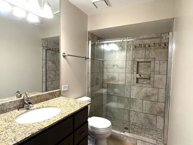 a bathroom with a granite countertop sink toilet and shower