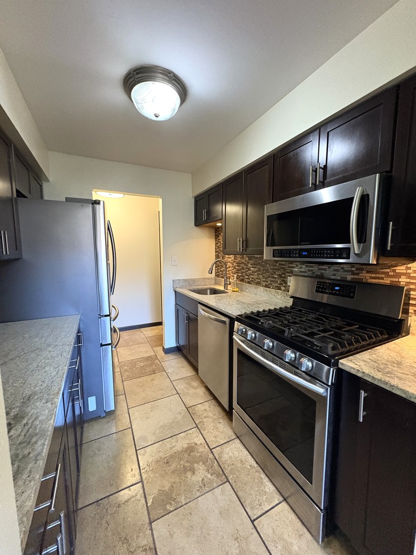 15805 Peggy Lane, Unit 9 Oak Forest, IL 60452 - Photo 3 of 20 a kitchen with stainless steel appliances granite countertop a stove a sink and a microwave