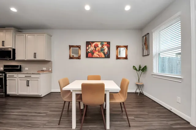 a kitchen with stainless steel appliances kitchen island granite countertop a stove top oven a refrigerator a sink and a dining table with wooden floor