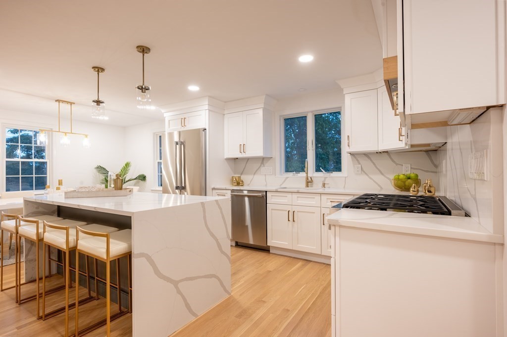 a kitchen with a stove a sink a kitchen island and chairs with wooden floor