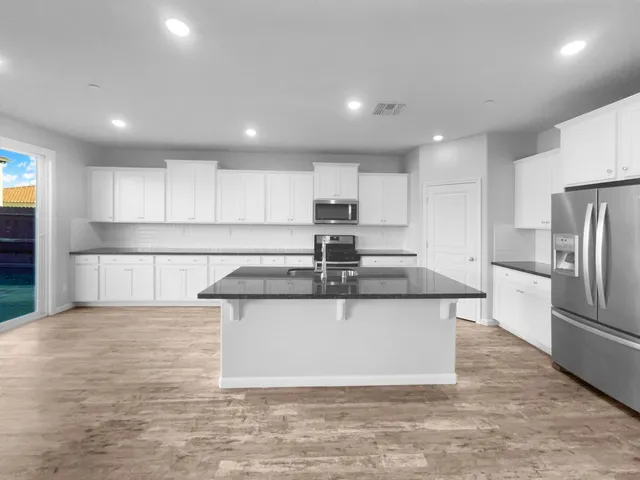 a kitchen with stainless steel appliances granite countertop a sink a stove a refrigerator and cabinets